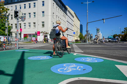 Žena an biciklu na biciklističkoj stazi. Saobraćajni znak za biciklističku stazu. Simbol bicikla na asfaltnom putu. Put rezervisan za bicikliste.