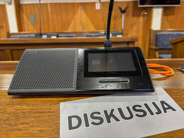 Sjednica u skupštini. Natpis DISKUSIJA pored poslaničkog mikrofona.