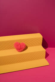 Podij od žutog rebrastog papira s ružičastim plišanim srcem.