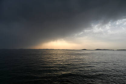 Valovi na moru sa dramatičnim oblacima iznad pri zalasku sunca. Nevrijeme. Olujno vrijeme na moru, pogled s broda. Kišni ljetni dan.