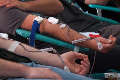 Dobrovoljni davaoci krvi daruju krv. Krupni plan ruku u toku darivanja krvi.