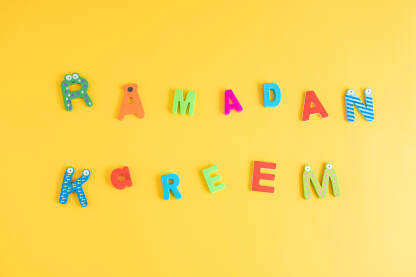 Internacionalna ramazanska čestitka od dječijih slova u bojama za igru na žutoj podlozi.