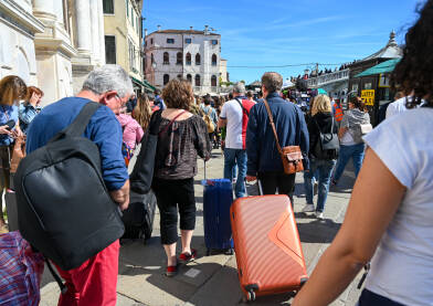 Turisti s torbama i koferima u gradu. Gužva na ulici u Veneciji, Italija. Turisti istražuju grad.
