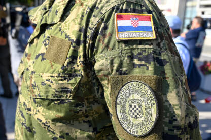 Oružane snage Republike Hrvatske tokom službene ceremonije. Hrvatska zastava na maskirnoj uniformi. Grb na ramenu vojnika.