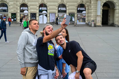 Mladi ljudi prave selfie u gradu. Fotografisanje sa mobilnim telefonom. Mladići i djevojke na trgu.
