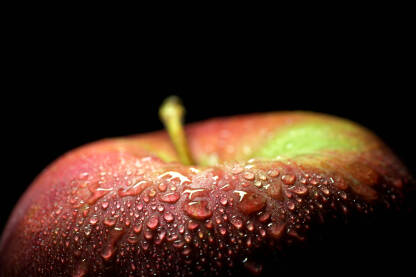 Makro fotografija jabuke sa kapljicama vode na crnoj pozadini