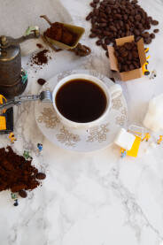 Mali radnici sa šoljicom kafe, kockicama šećera, mlinom za kafu i kafom na stolu.