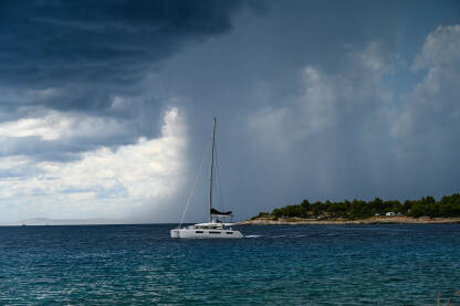 Jedrilica na moru za vrijeme oluje. Jedrilica na vodi s tamnim olujnim oblacima u pozadini.