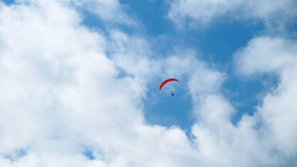 Padobranac sa crvemnim padobranom na nebu.