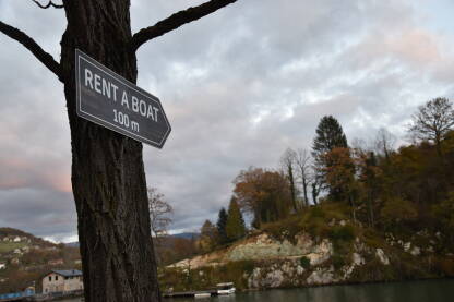 Znak za iznajmljivanje čamca sa prirodnim krajolikom u pozadini.