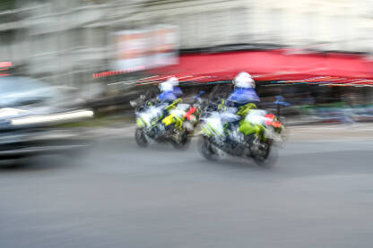 Zamućena fotografija policajaca na motociklima. Policijska patrola na ulici u Parizu, Francuska.