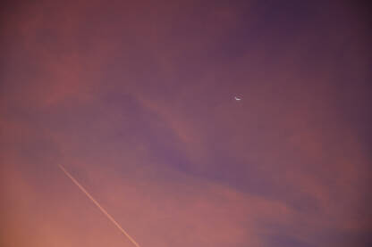 Narandžasto nebo tokom izlaska sunca. Mjesec i avion na nebu rano ujutro. Zora.