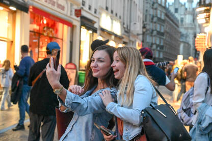 Brisel, Belgija: Djevojke prave selfie mobilnim telefonom u gradu. Prijateljice snimaju selfie. Turisti koriste mobilni telefon za selfie u centru grada.