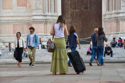 Turistkinja na ulicama Bolonje, Italija. Djevojka sa koferom stoji na ulici.