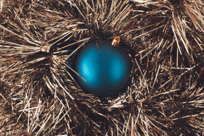 Plava sjajna kuglica za bor na metalik zlatnom ukrasu. Novogodišnja, božićna čestitka.