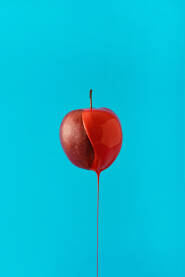 Svježa jabuka niz koju se sliva crvena boja.