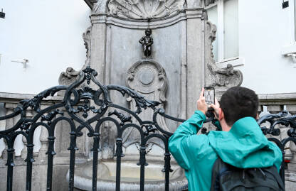 Bruxelles, Belgija. Turist fotografira Maneken Pis, simbol Brisela. Poznata znamenitost, skulptura od bronzane fontane u centru grada.