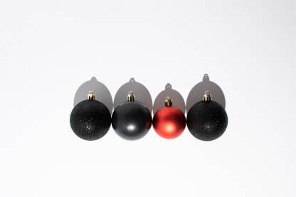 Četiri sjajne ukrasne kuglice poredane na bijeloj pozadini. Novogodišnja, božićna čestitka.