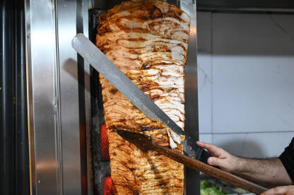 Pečeno donner meso na rotiranom ražnju. Kuhar reže meso. Ukusni donner kebab.