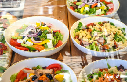 Svježa salata u zdjelama u restoranu. Svježa salata u zdjelama u restoranu. Nasjeckano povrće u zdjeli. Paradajz, luk, sir, rukola, masline.