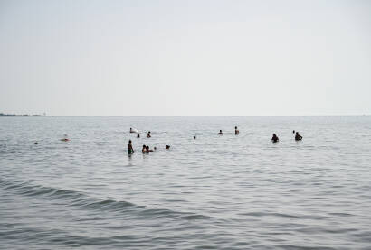 Shëngjin, Albanija. Ljudi plivaju u moru i sunčaju se na plaži. Turisti na ljetnom godišnjem odmori. Popularna turistička destinacija na Jadranskom moru u Albaniji.