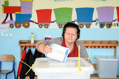 Žena glasa na izborima. Glasački listići. Izbori u BiH.