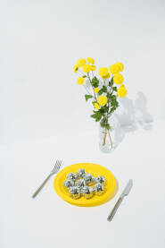 Buket žutog cvijeća i sjajne disko kugle na žutom plastičnom tanjuru.