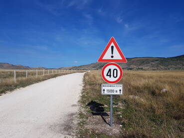 Saobraćajni znakovi koji označavaju ograničenje brzine kretanja vozila na 40 km/h i opreznu vožnju zbog kretanja po makadamskoj cesti u dužini od 15.000 m, tj. 15 km