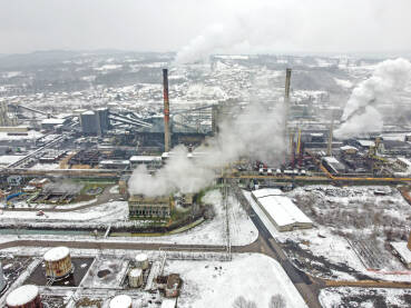 Dimnjaci iz tvornice zagađuju okoliš. Industrijsko onečišćenje zraka iz fabrike. Otrovni dim iz dimnjaka u industrijskoj zoni tokom zime. Industrijski kompleks, snimak dronom.